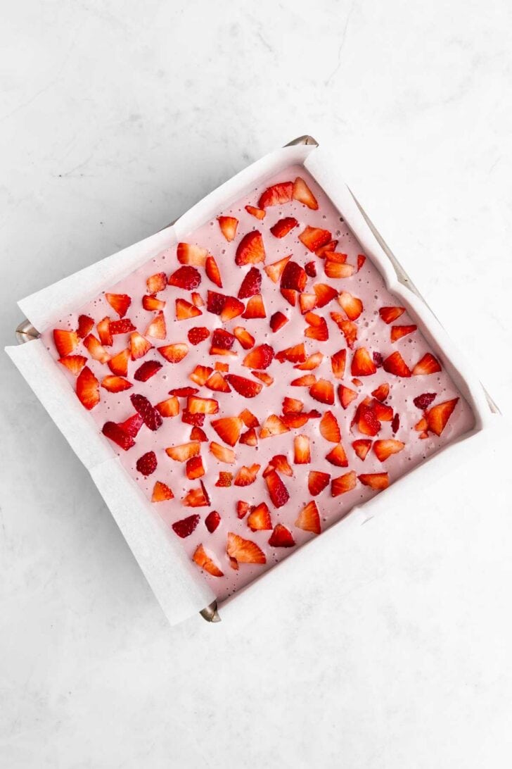 no-bake strawberry cheesecake brownies pressed inside a square baking pan