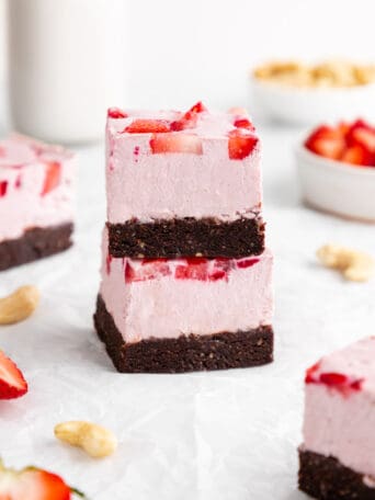 a stack of two no-bake strawberry cheesecake brownies with dates, cocoa, and cashews