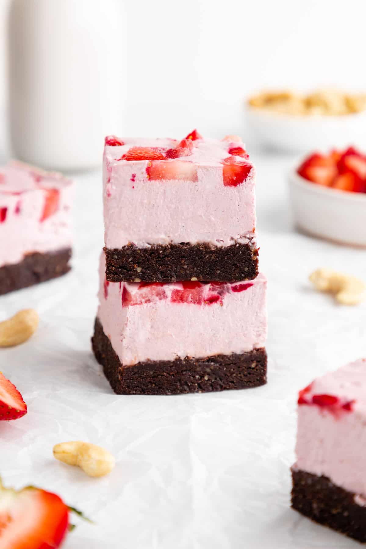 a stack of two no-bake strawberry cheesecake brownies with dates, cocoa, and cashews