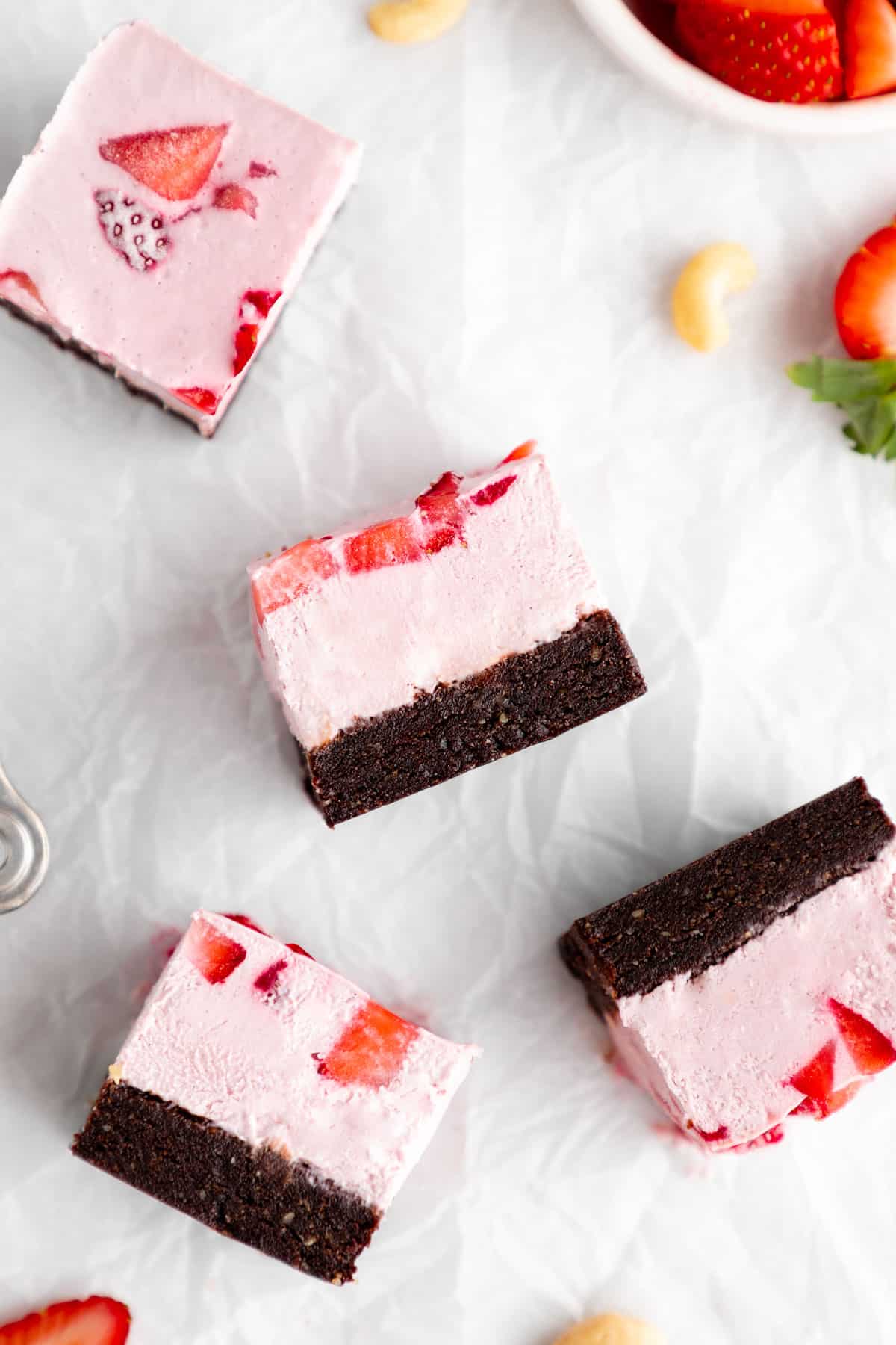 slices of no-bake strawberry cheesecake brownies on white parchment paper