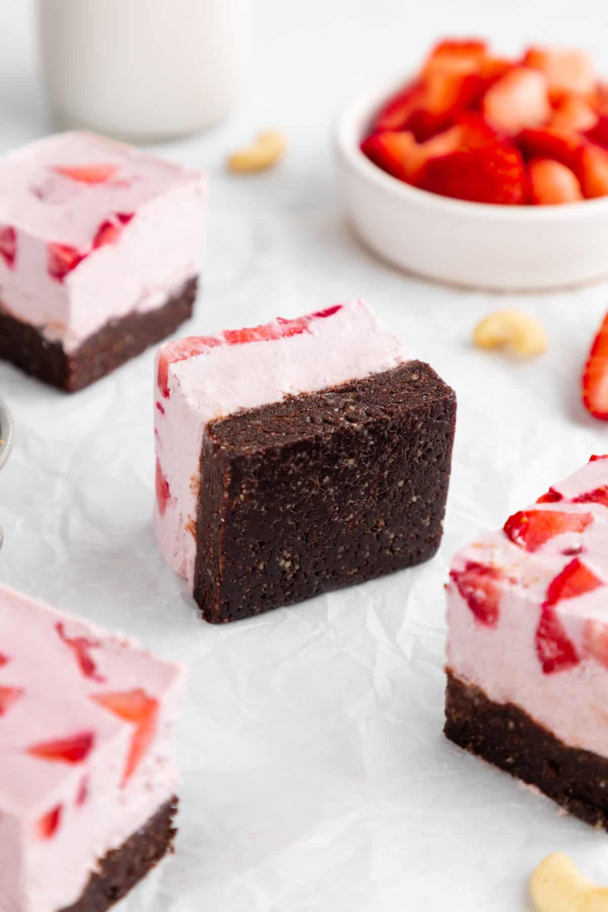 a no-bake strawberry cheesecake brownie laying on its side on white parchment paper