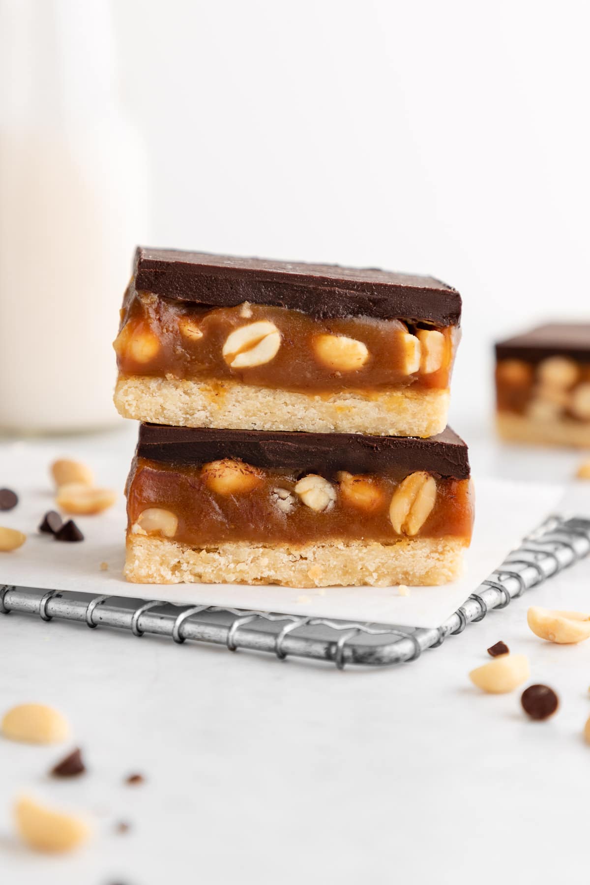 a stack of two vegan snickers cookie bars with caramel and peanuts