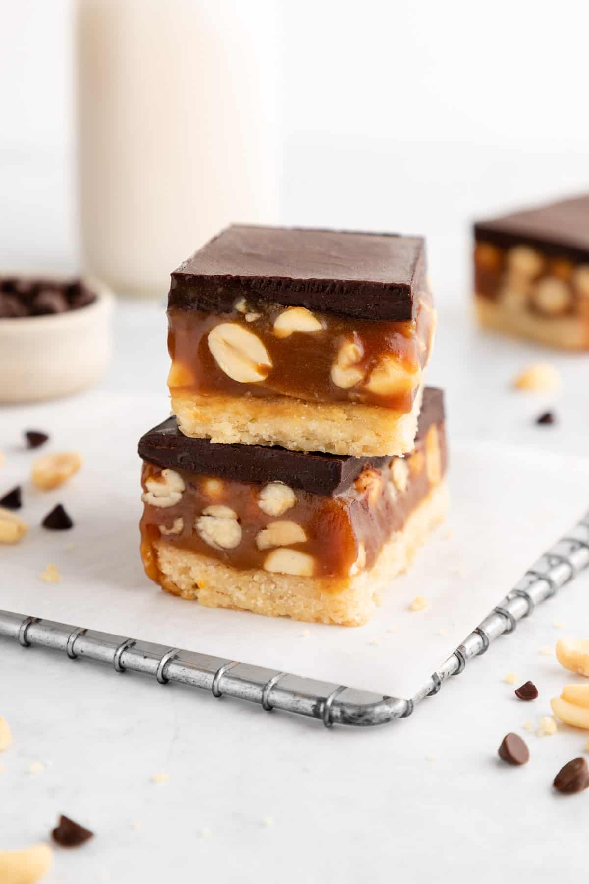 a stack of two vegan snickers cookie bars with caramel and peanuts