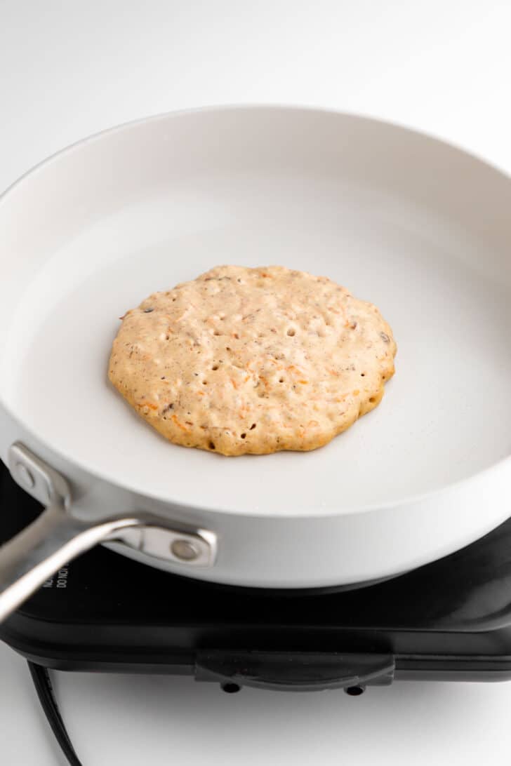 vegan carrot cake pancakes frying on a ceramic pan