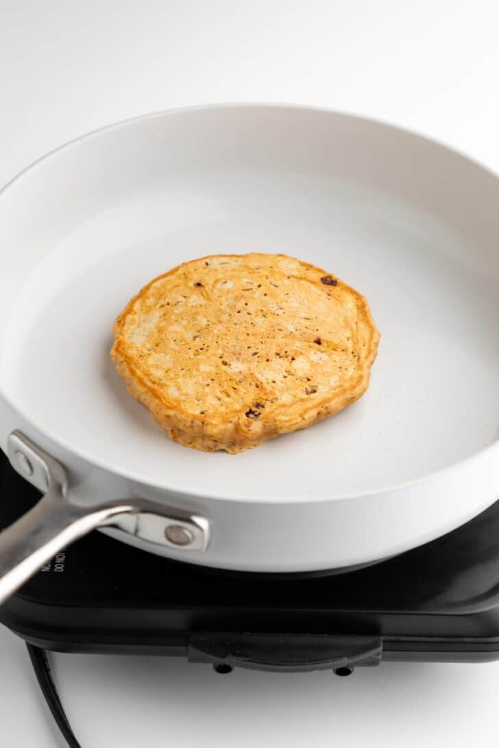 frying vegan carrot cake pancakes on a ceramic pan
