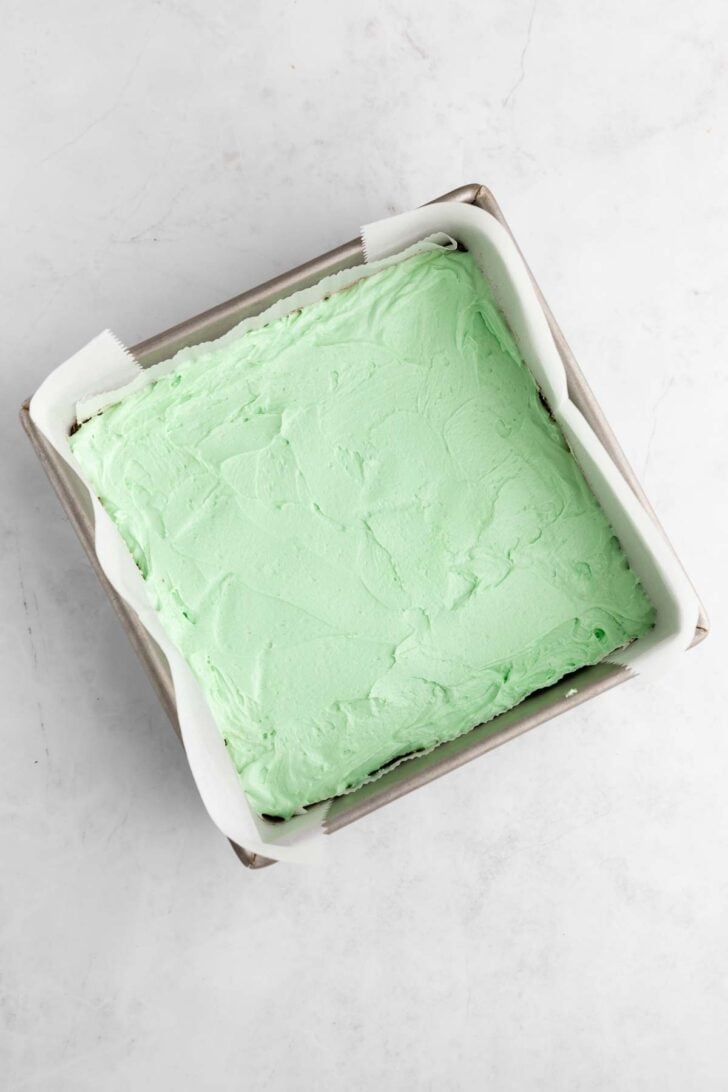vegan mint nanaimo bars with mint buttercream frosting inside a square baking pan