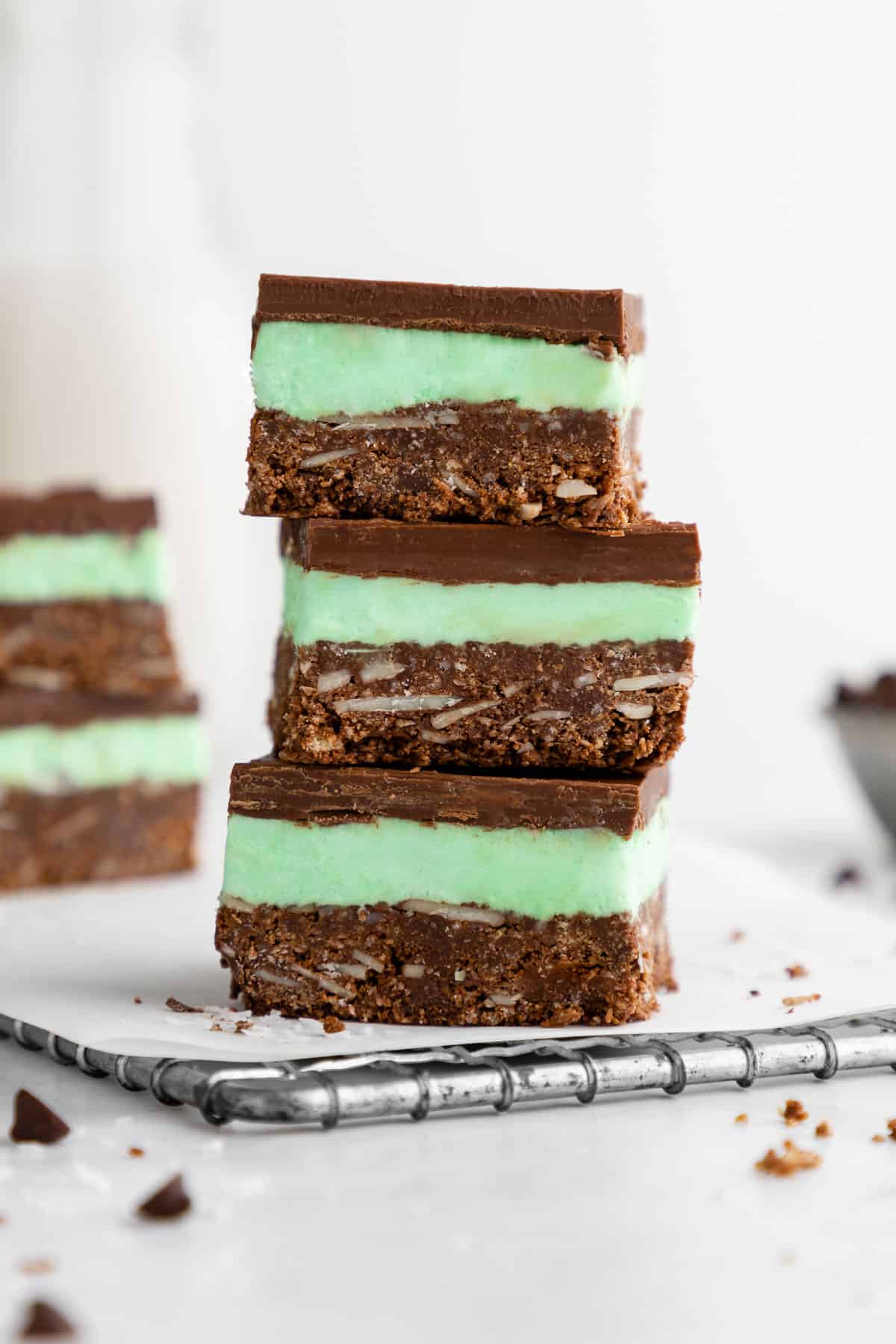 a stack of three vegan mint nanaimo bars with mint buttercream frosting and chocolate ganache