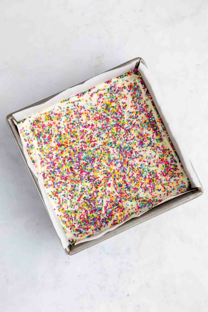 birthday cake rice krispie treats with white chocolate and sprinkles on top inside a baking pan