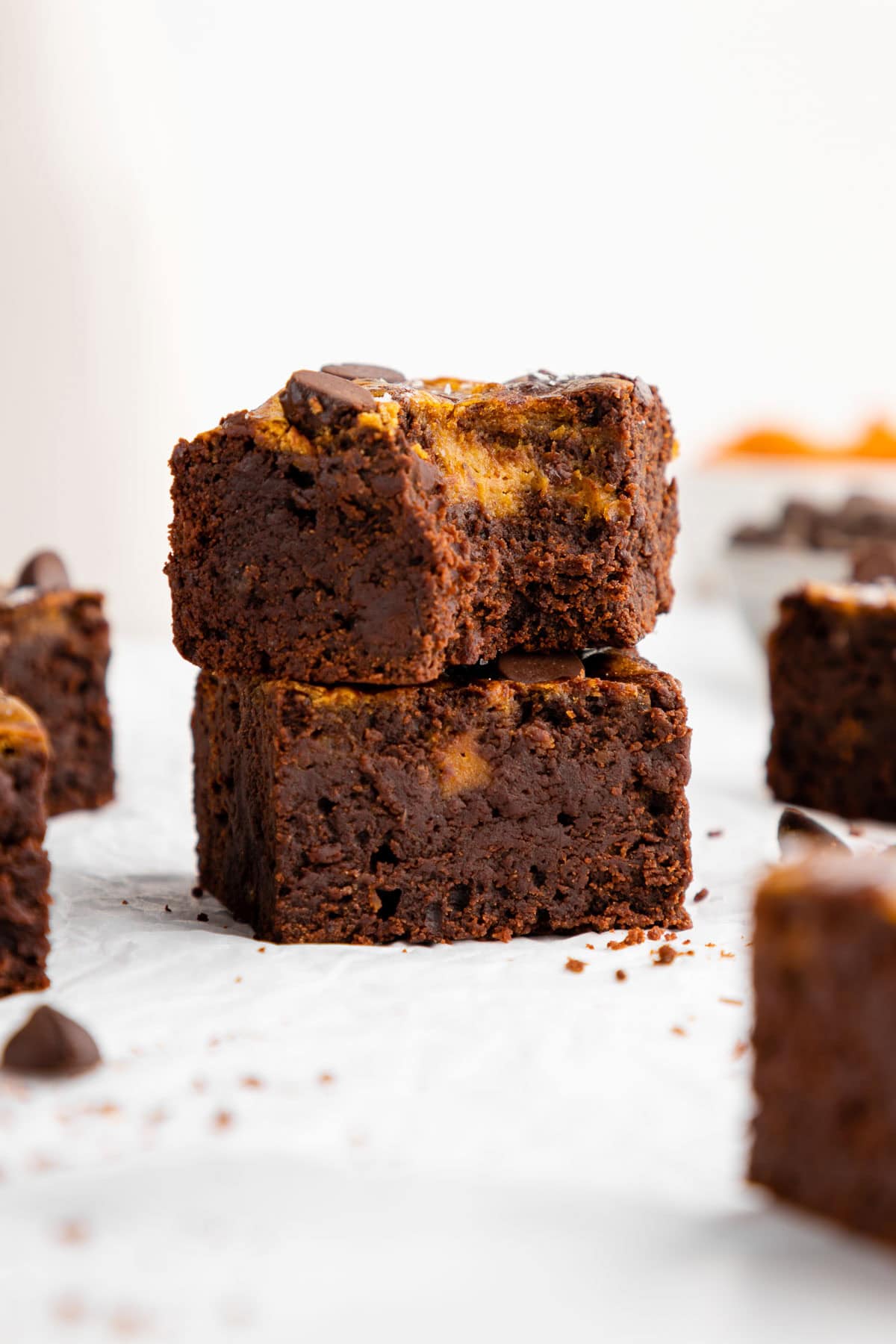 a stack of vegan pumpkin cheesecake brownies with a bite taken out of the top one