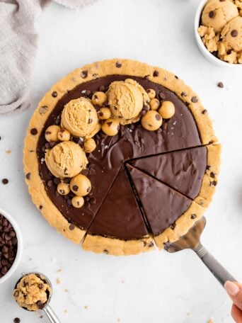 slicing into a healthy no-bake cookie dough tart with vegan chocolate ganache filling
