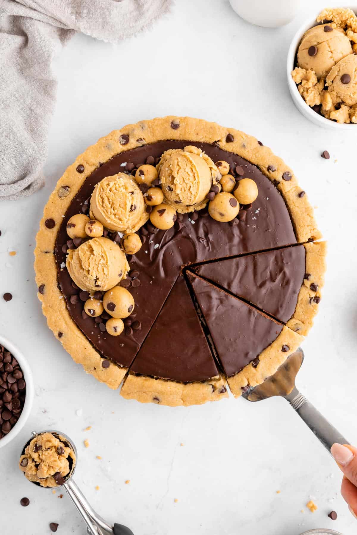 slicing into a healthy no-bake cookie dough tart with vegan chocolate ganache filling