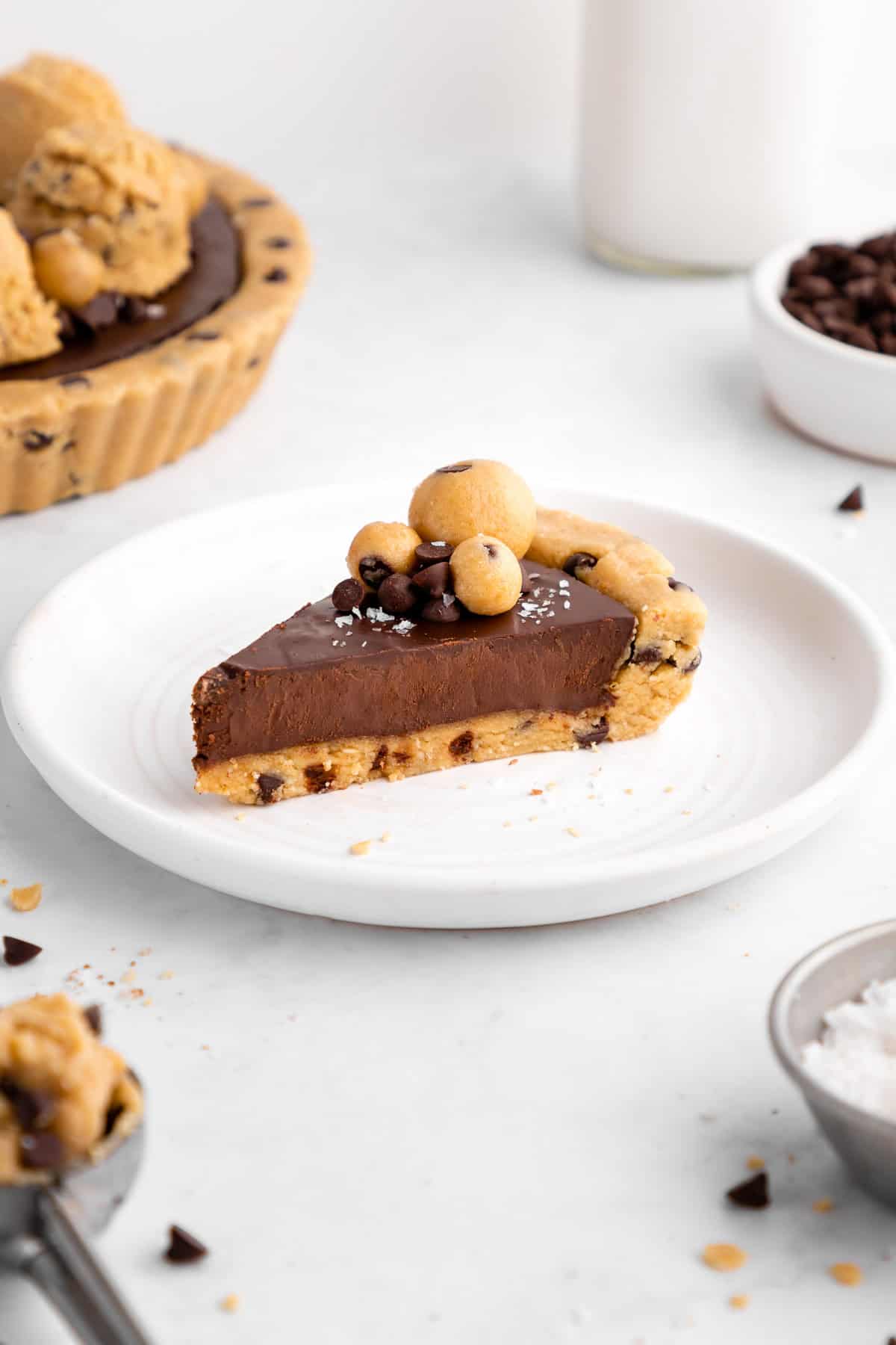 a slice of a healthy no-bake cookie dough tart with vegan chocolate ganache