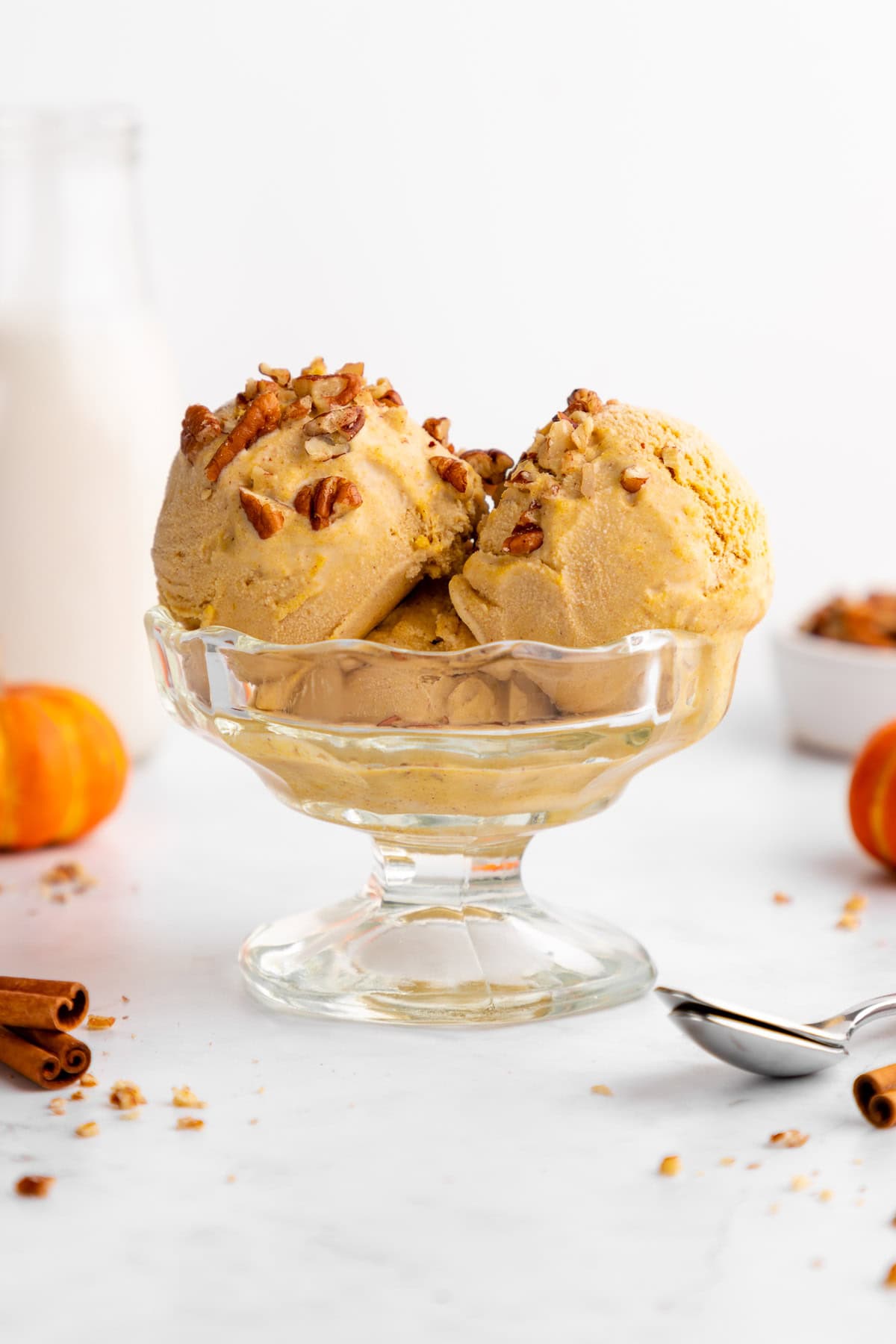 vegan pumpkin ice cream scoops inside a glass sundae bowl