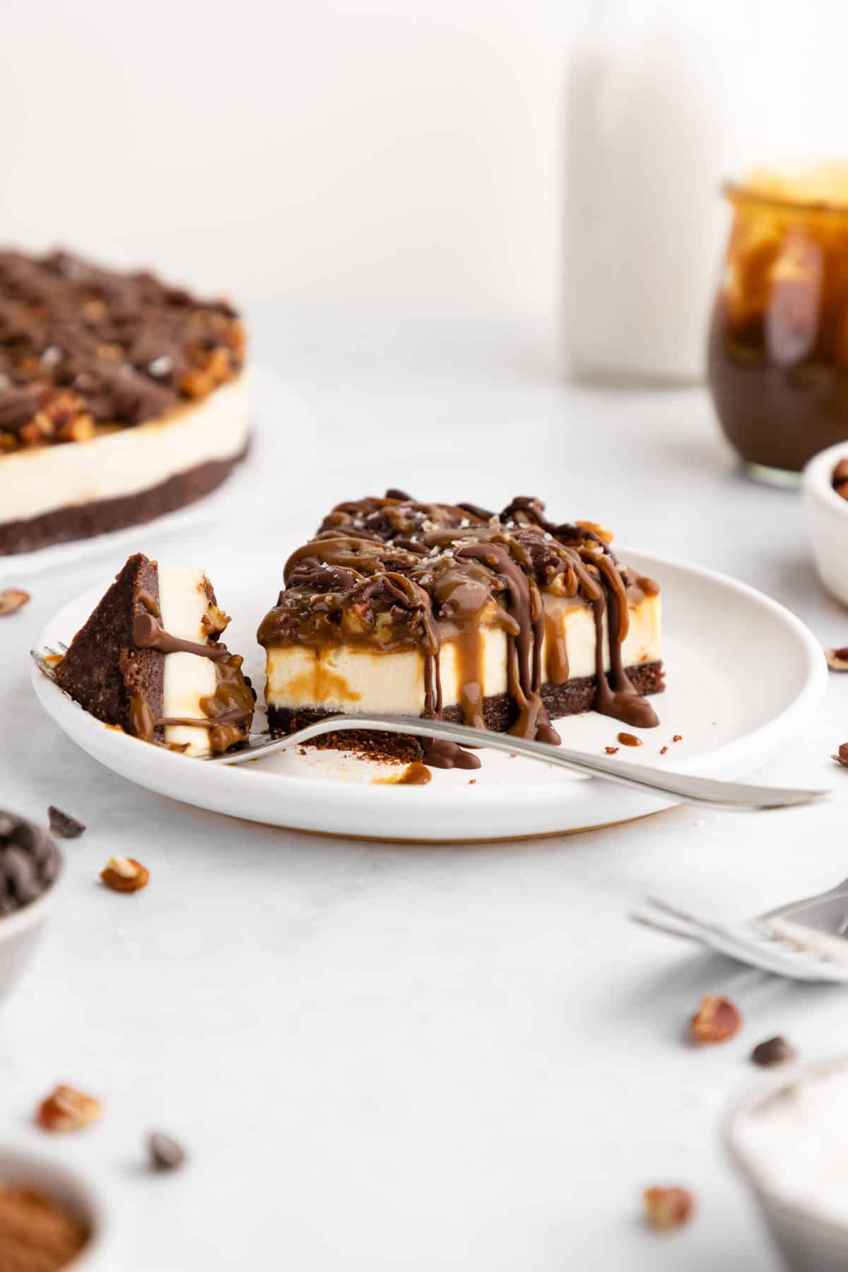 a partially eaten slice of no-bake turtle cheesecake on a plate with a fork