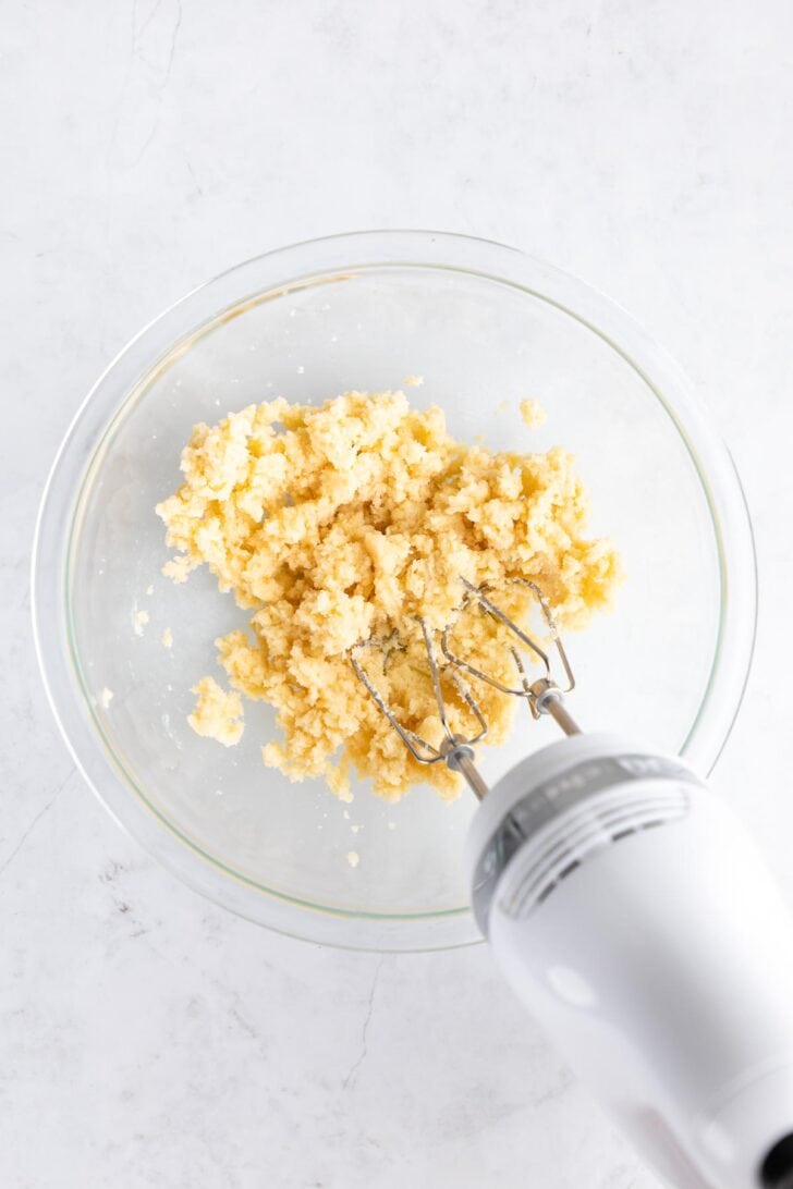 a handheld electric mixer creaming vegan butter and sugar together