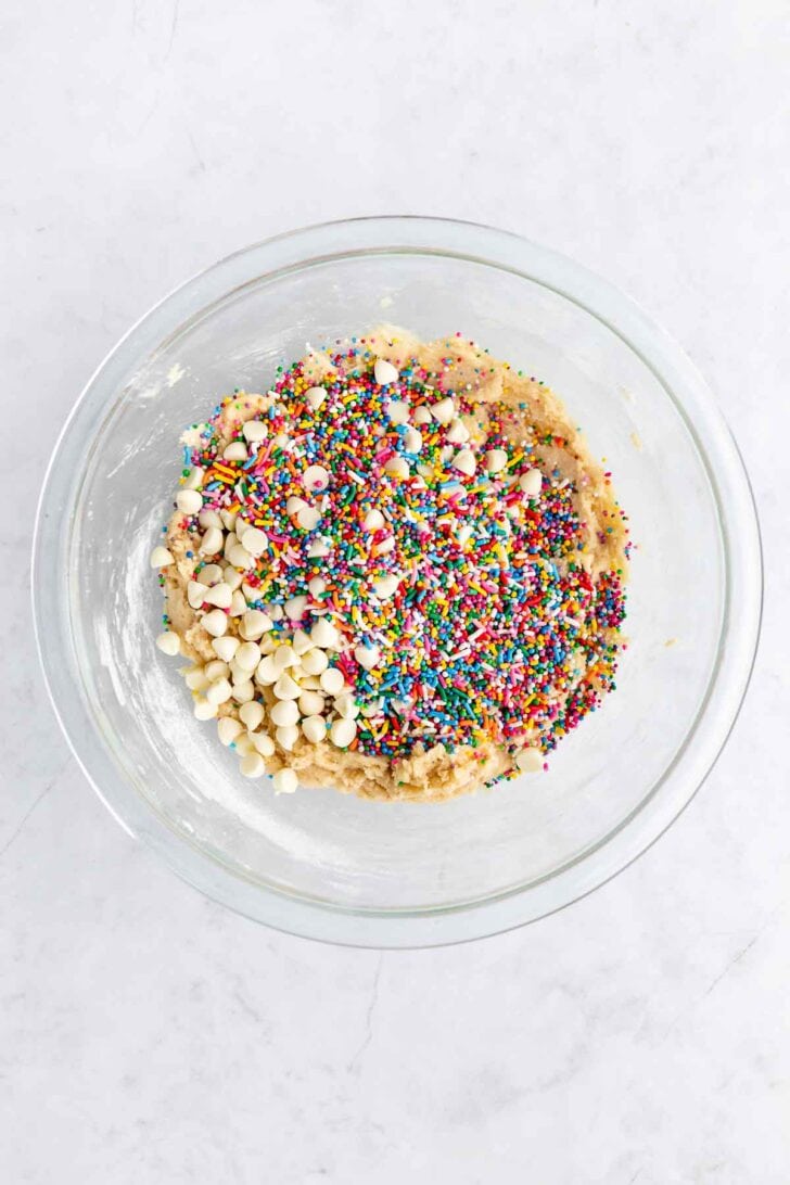 vegan birthday cake cookie dough with white chocolate chips and sprinkles inside a glass bowl