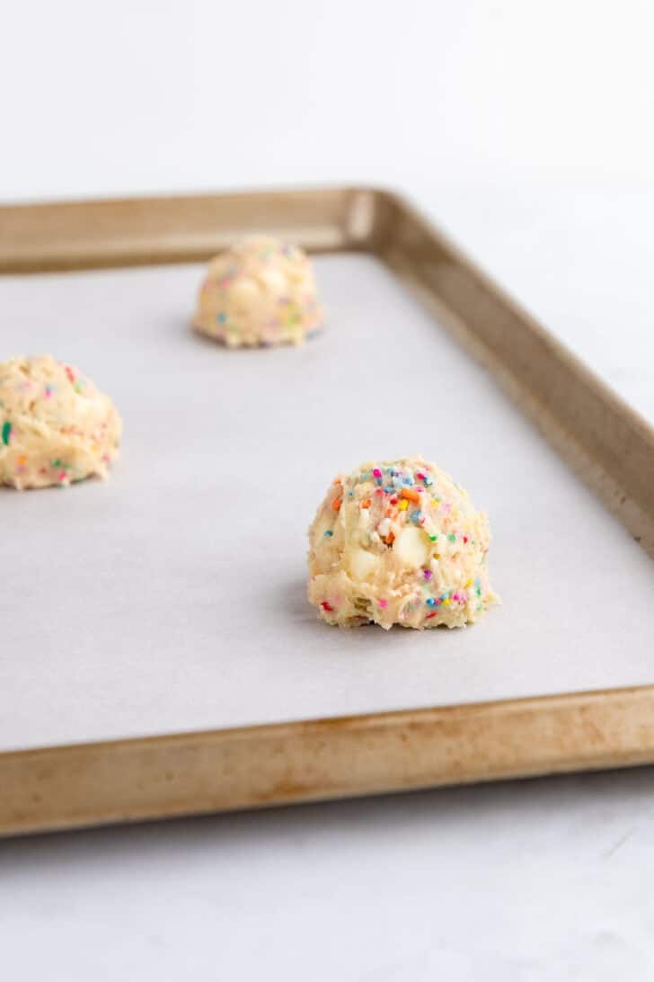 balls of vegan birthday cake cookie dough on a baking sheet