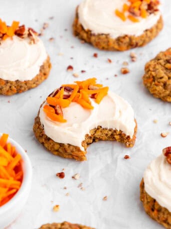 vegan carrot cake cookie with cream cheese frosting with a bite taken out of it