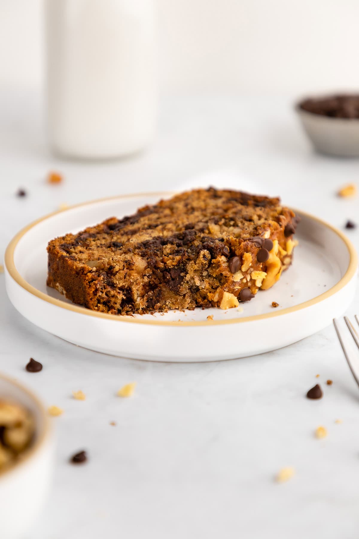 a slice of vegan chocolate chip banana bread with a bite taken out of it on a ceramic plate