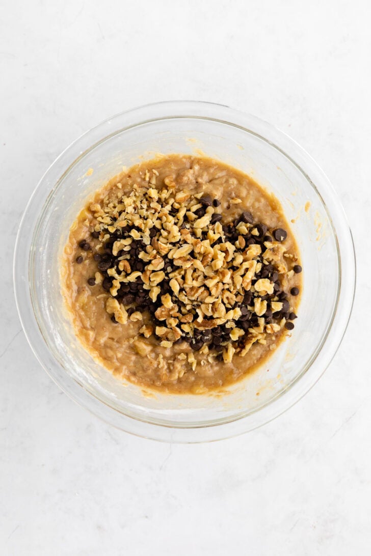 vegan banana bread batter with chocolate chips and walnuts inside a glass bowl