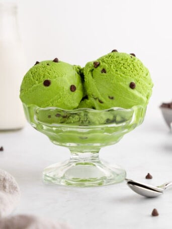 scoops of vegan matcha ice cream with chocolate chips inside a sundae glass