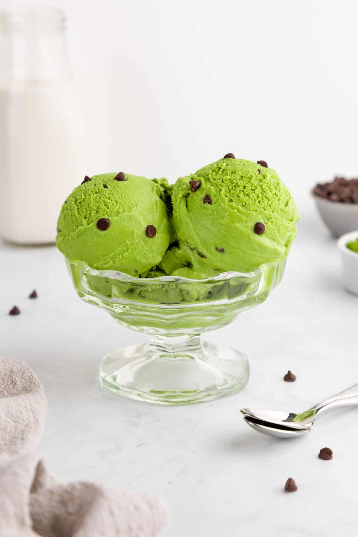 scoops of vegan matcha ice cream with chocolate chips inside a sundae glass