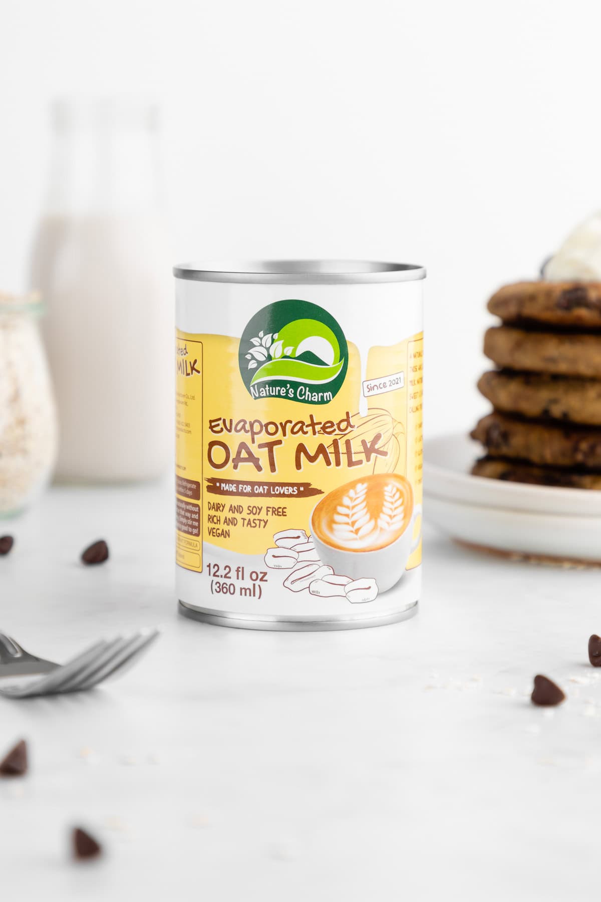 a can of Nature's Charm evaporated oat milk beside a stack of oatmeal chocolate chip pancakes