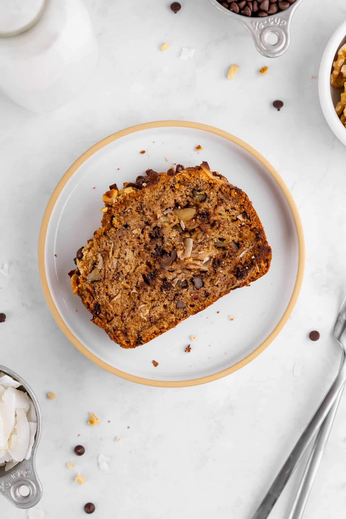 a slice of chunky monkey banana bread on a plate with coconut, walnuts, and chocolate chips