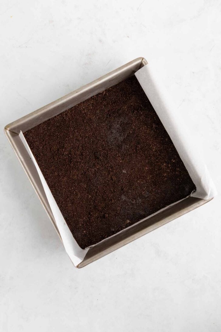 pressing an Oreo crust inside a baking dish