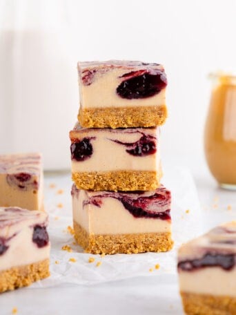 a stack of three no-bake peanut butter and jelly cheesecake bars with a berry swirl