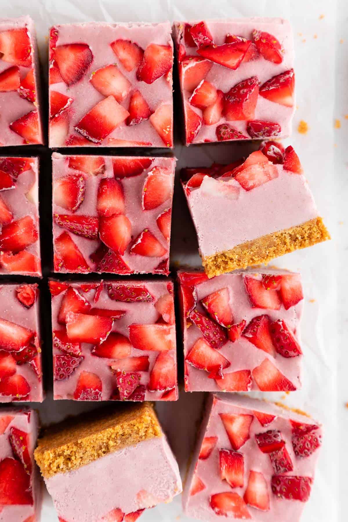 a pile of no-bake strawberry cheesecake bars with graham cracker crust