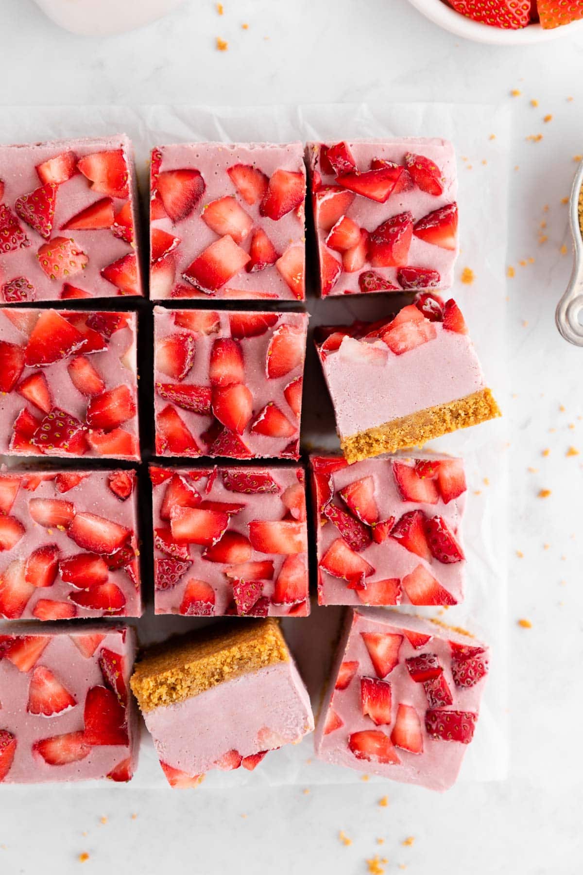 a pile of no-bake strawberry cheesecake bars with graham cracker crust