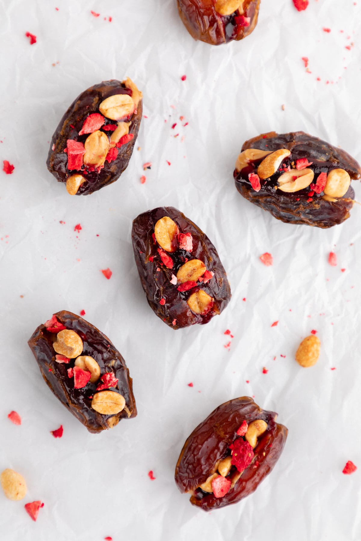 PB&J stuffed dates with berry jam, peanuts, and freeze-dried fruit on parchment paper
