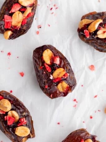 PB&J stuffed dates with berry jam, peanuts, and freeze-dried fruit on parchment paper