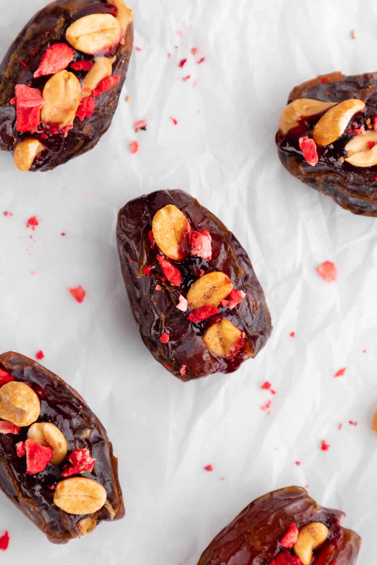 PB&J stuffed dates with berry jam, peanuts, and freeze-dried fruit on parchment paper