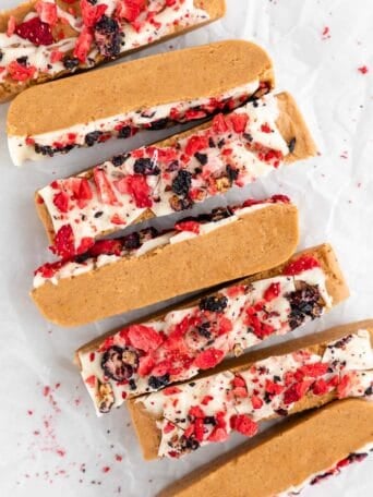 a close up of homemade peanut butter and jelly protein bars with white chocolate and freeze dried fruit