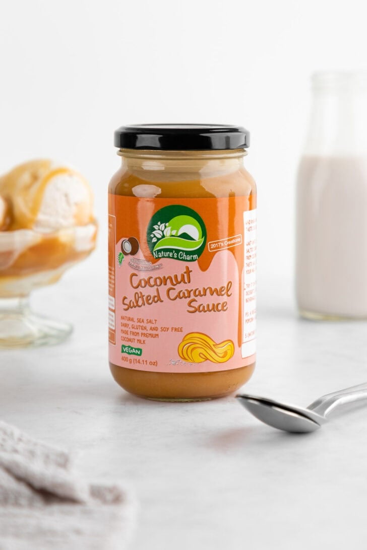 a jar of Nature's Charm coconut salted caramel sauce with a vegan salted caramel ice cream sundae