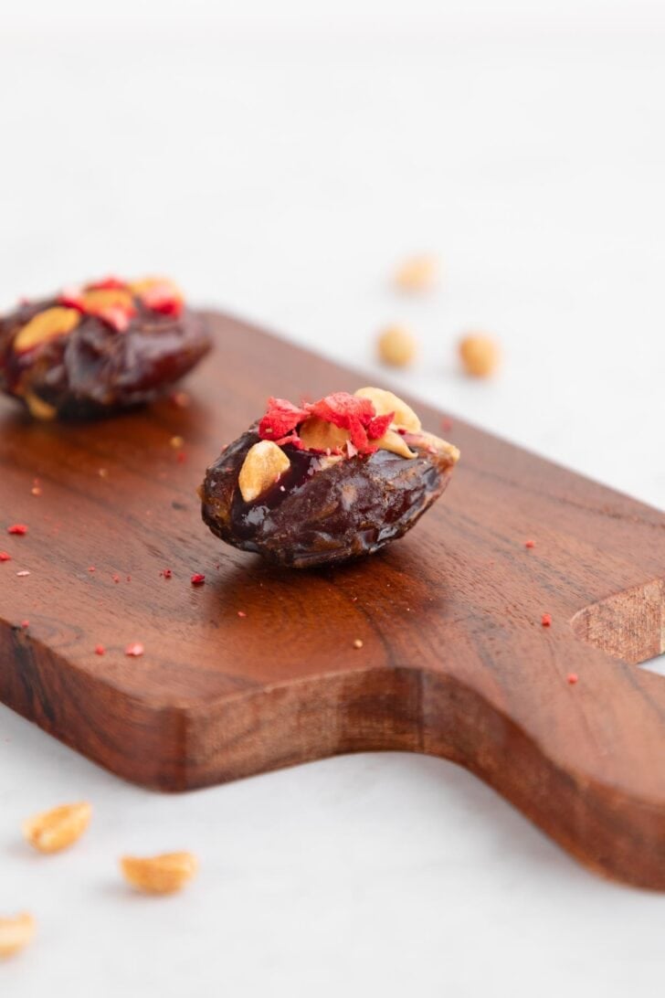 a medjool date stuffed with peanut butter and jelly on a wood cutting board