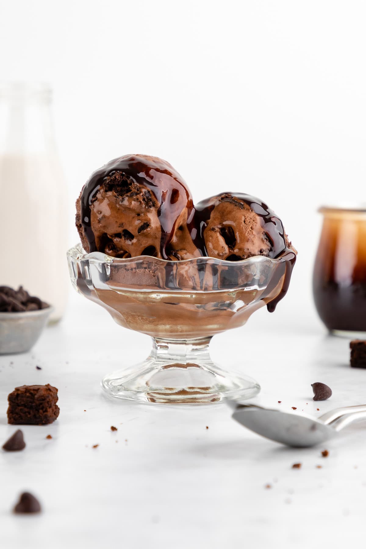vegan chocolate fudge brownie ice cream inside a sundae glass with coconut chocolate fudge sauce on top