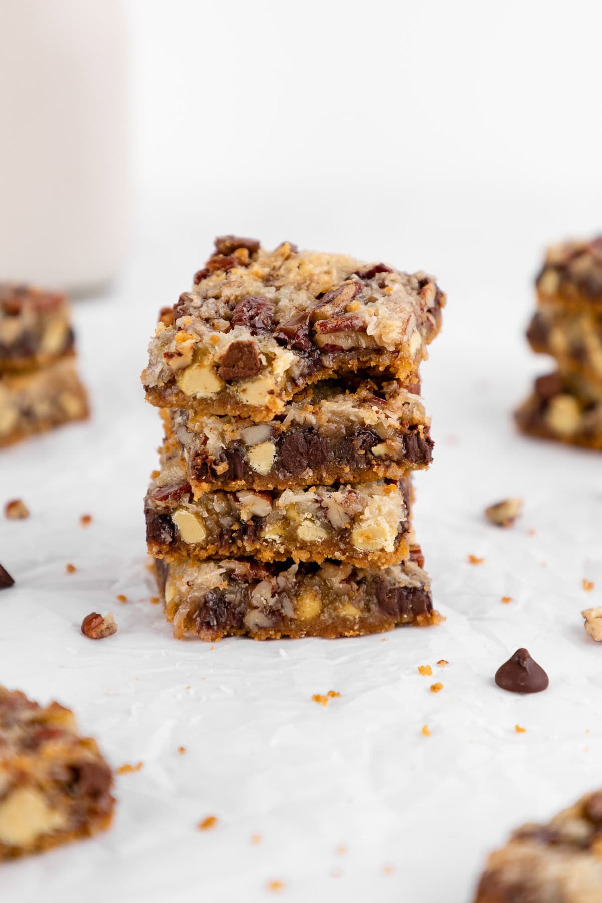 a stack of vegan seven layer magic cookie bars with a bite taken out of the top one