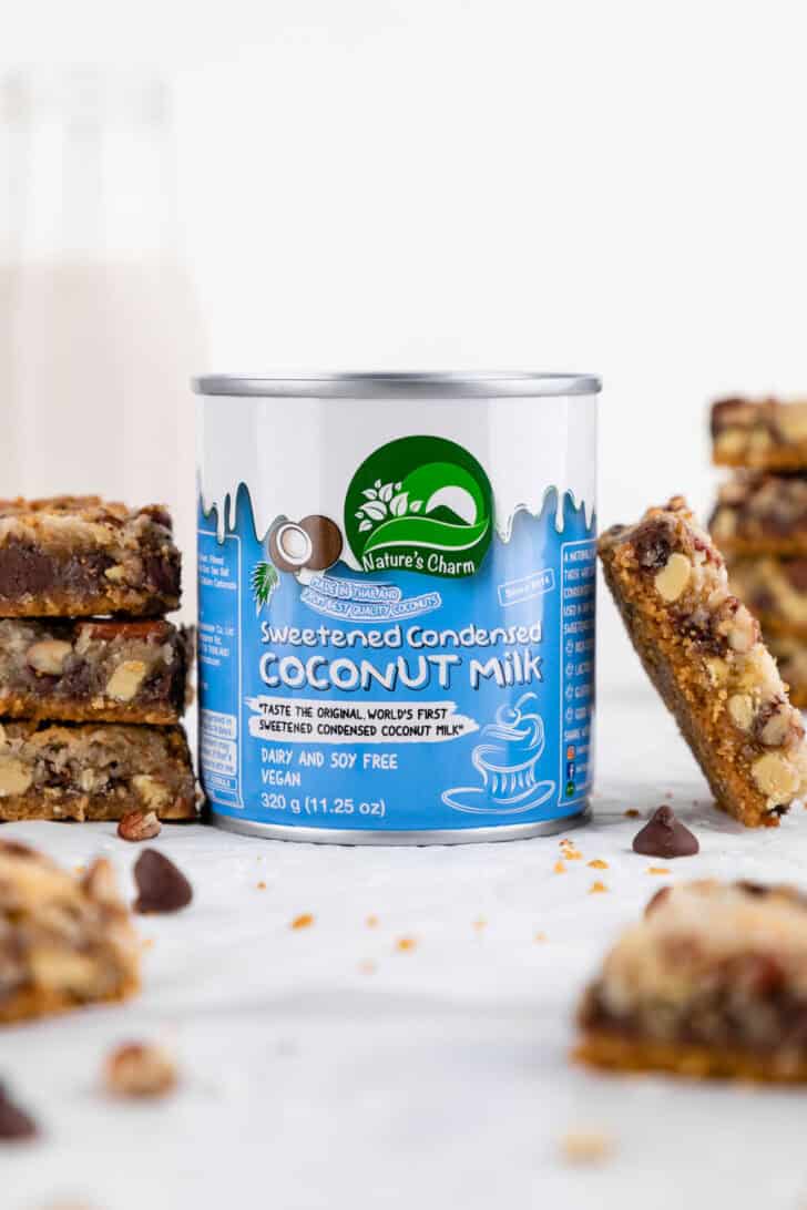 a can of Nature's Charm sweetened condensed coconut milk surrounded by vegan seven layer magic cookie bars