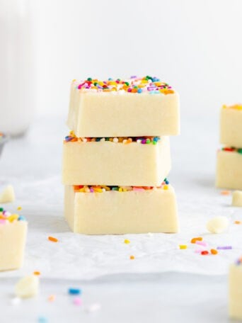 a stack of three vegan white chocolate cake batter fudge squares with sprinkles