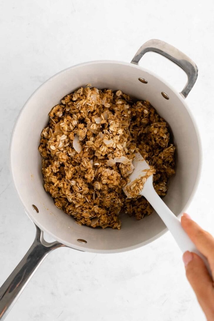 mixing ingredients in a saucepan for homemade coconut chocolate chip granola bars